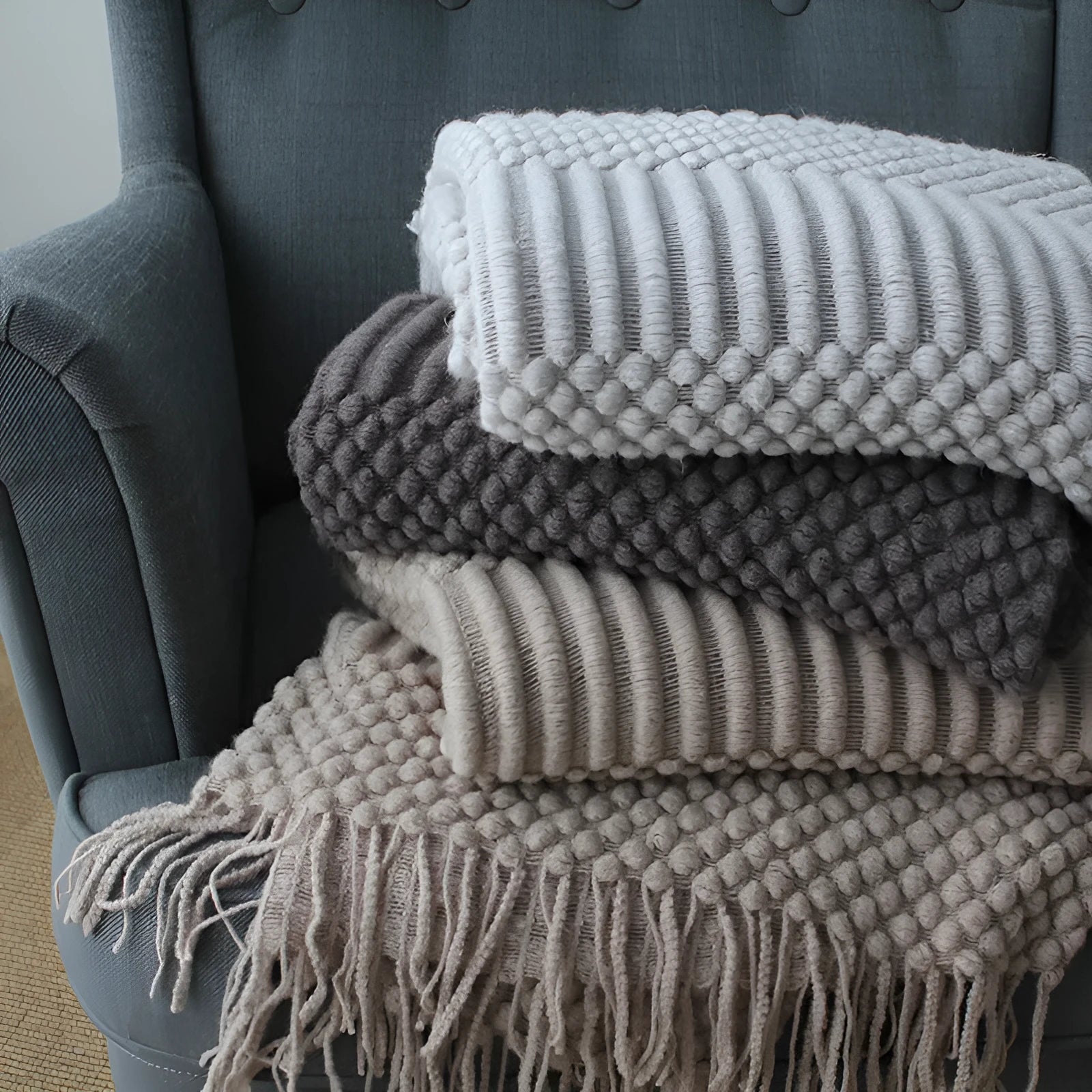 Small light grey polyester fleece blanket folded on a sofa