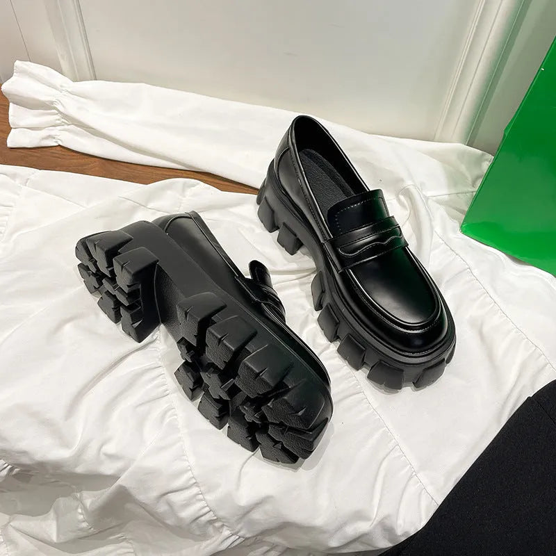 A pair of British style wide fit loafers in either matte or glossy patent leather with a shallow opening and rubber sole.