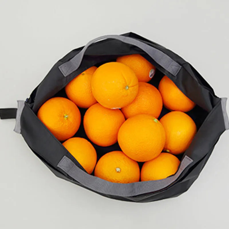 Mini reusable compact grocery bag in light blue, folded and open, made from water-repellent nylon cloth.
