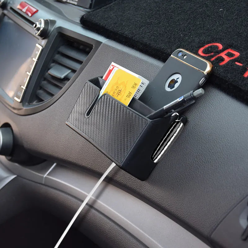 Black PVC carbon fibre pattern phone storage box with reusable adhesive on a car seat surface