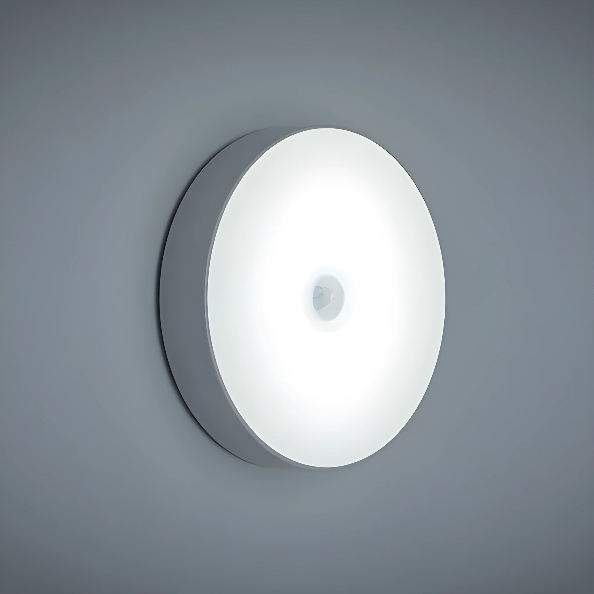 Small round white motion sensor night light with USB charging cable and adhesive tape.