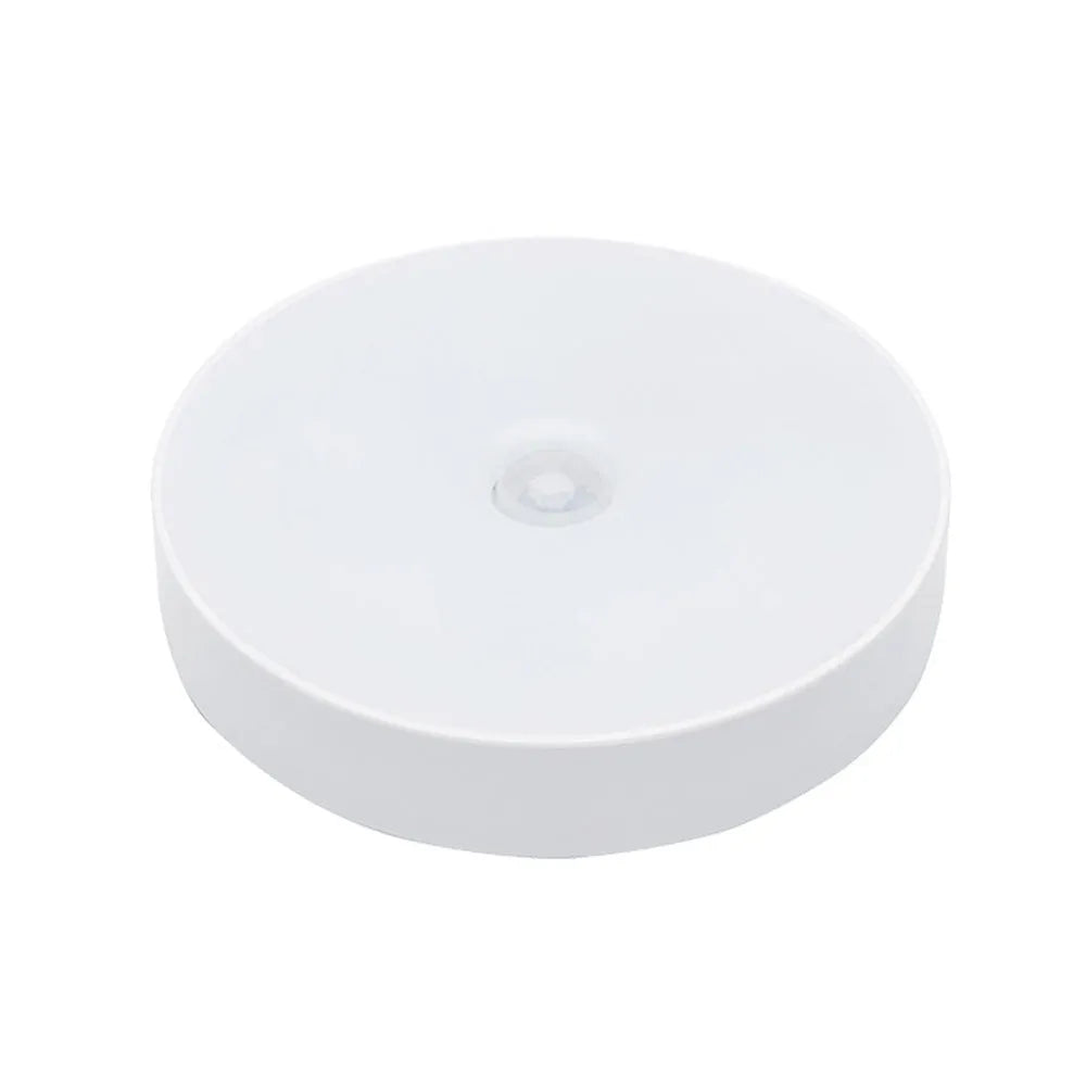 Small round white motion sensor night light with USB charging cable and adhesive tape.