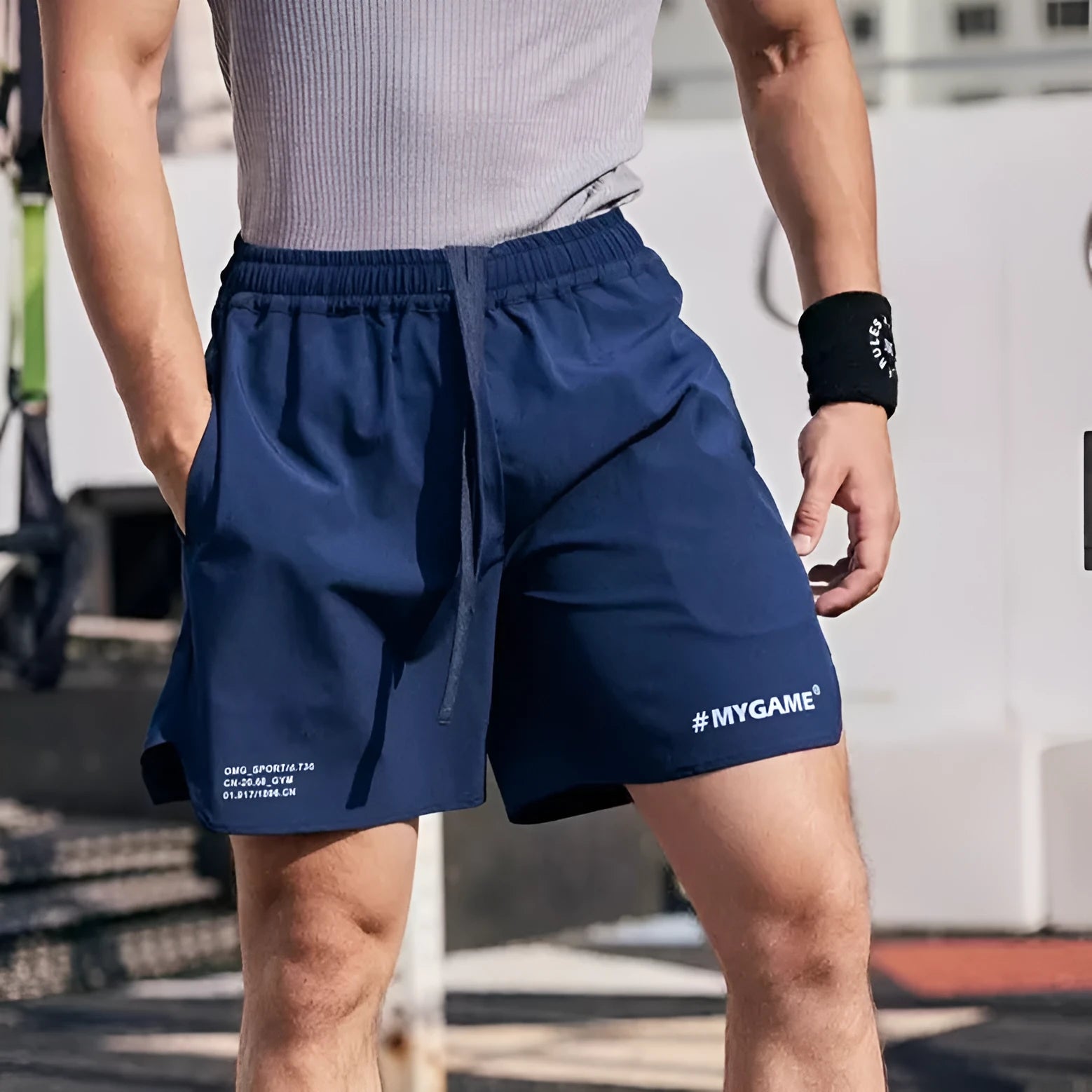 Man wearing grey elastic training shorts in a gym setting, demonstrating the short-length, quick-dry design.