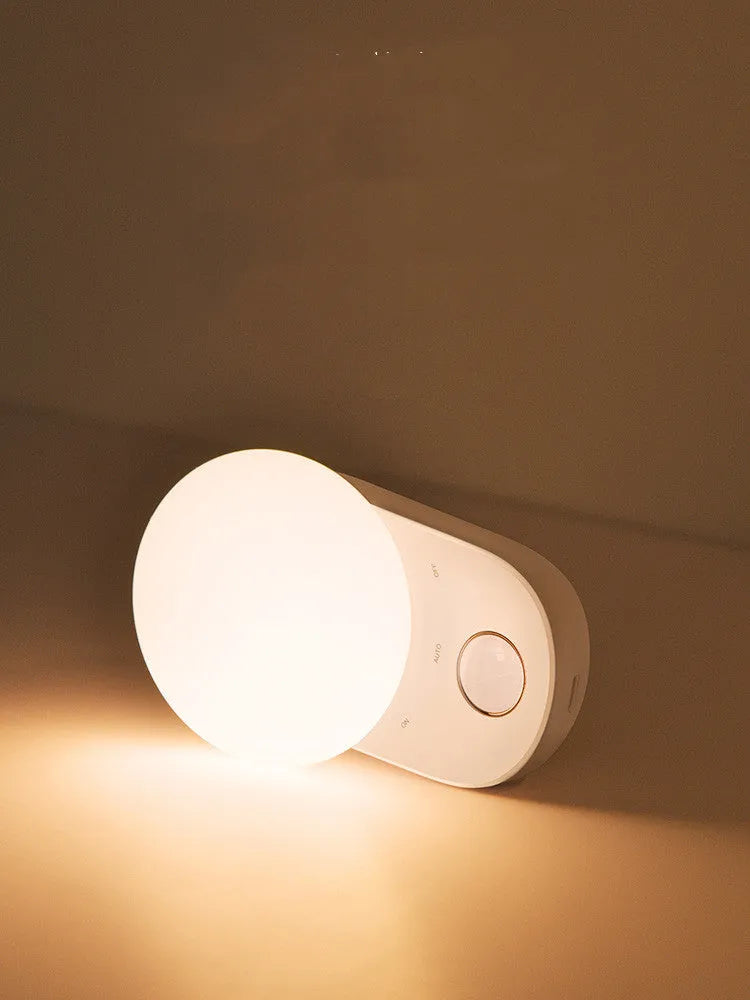 White Baseus rechargeable motion sensor bedside night light with LED glow, shown on a table.