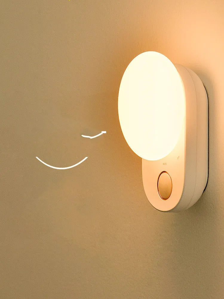 White Baseus rechargeable motion sensor bedside night light with LED glow, shown on a table.
