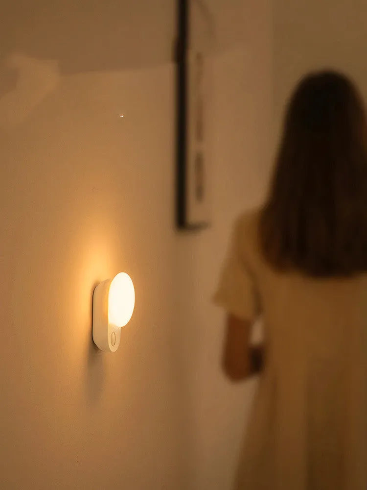 White Baseus rechargeable motion sensor bedside night light with LED glow, shown on a table.