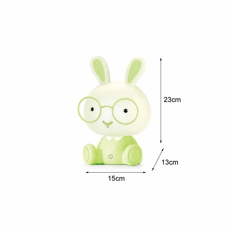 Blue plastic USB cartoon night light with a cute rabbit decoration wearing glasses on a desk.