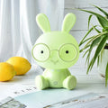 Blue plastic USB cartoon night light with a cute rabbit decoration wearing glasses on a desk.