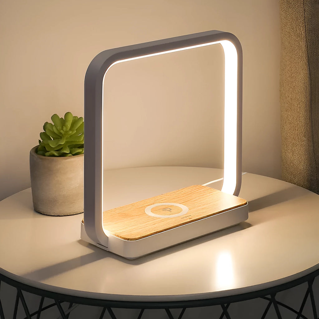 Modern white aluminium smart bedside lamp with touch control and USB cable on a wooden table.
