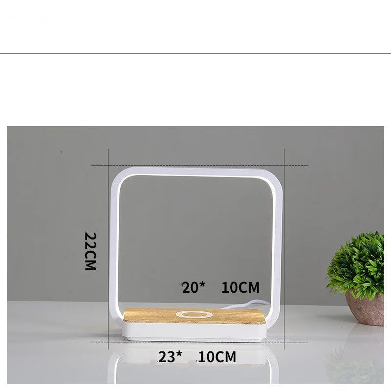 Modern white aluminium smart bedside lamp with touch control and USB cable on a wooden table.