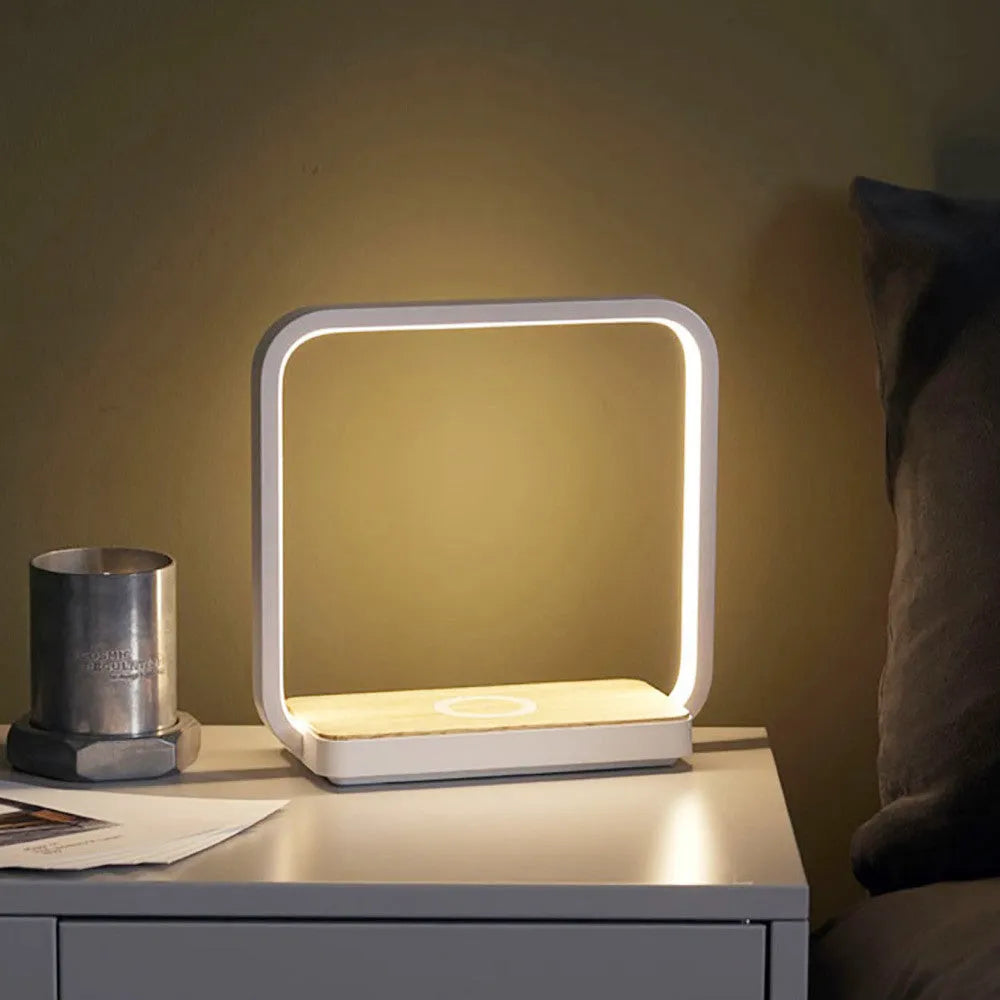 Modern white aluminium smart bedside lamp with touch control and USB cable on a wooden table.