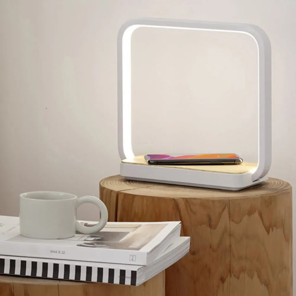Modern white aluminium smart bedside lamp with touch control and USB cable on a wooden table.