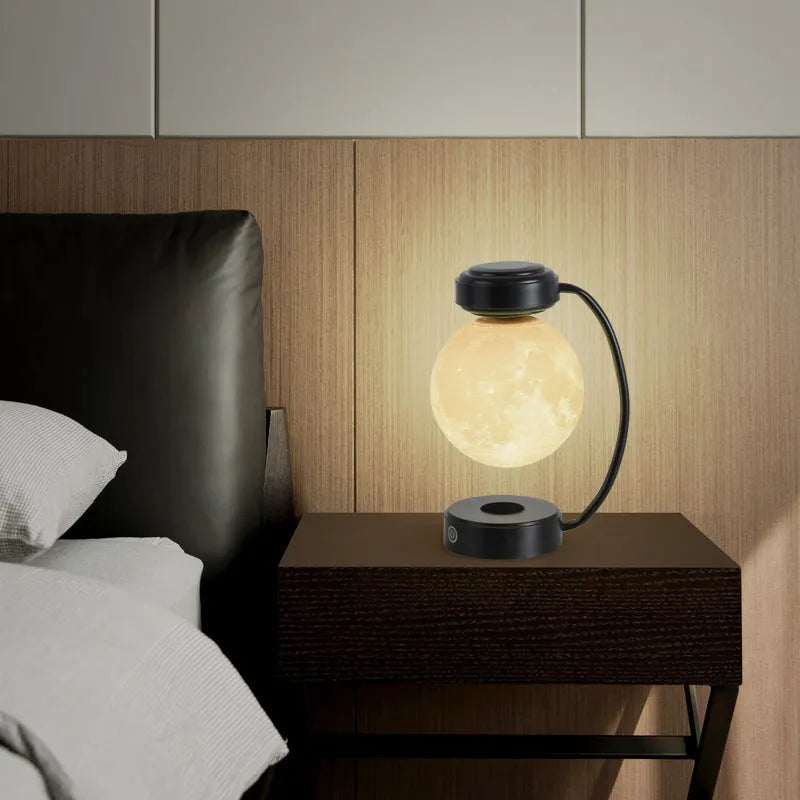 Black magnetic levitation moon lamp floating above base with golden LED illumination
