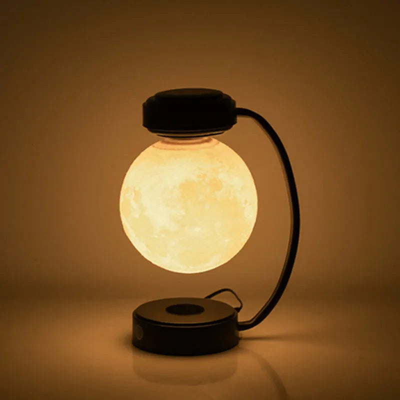 Black magnetic levitation moon lamp floating above base with golden LED illumination