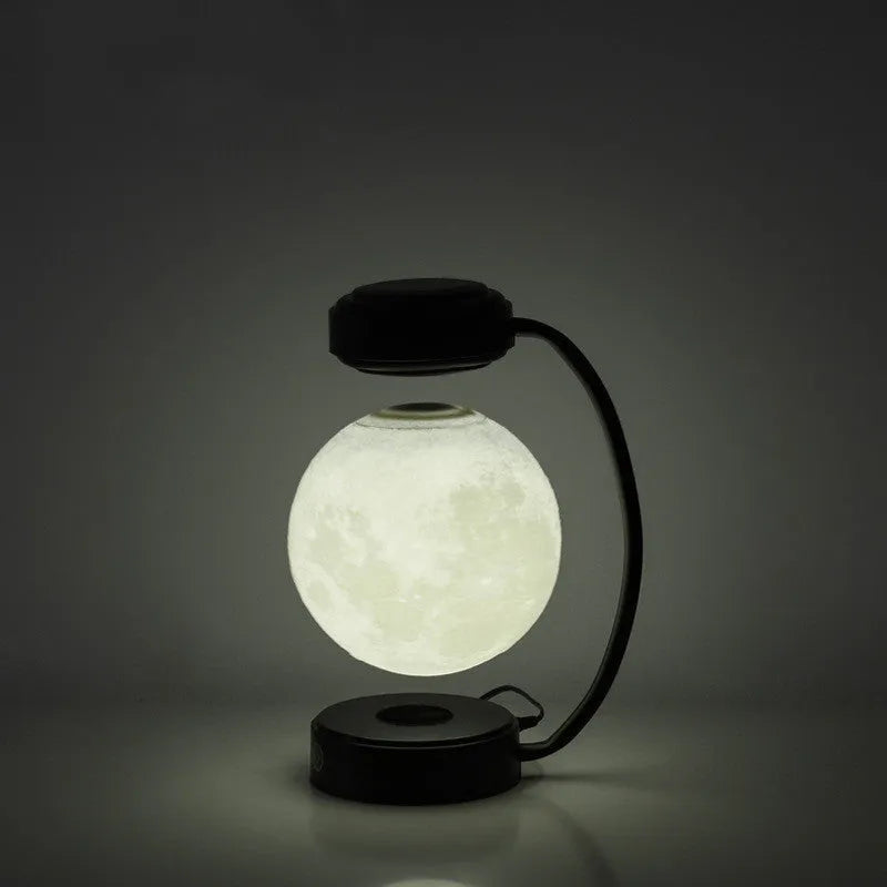 Black magnetic levitation moon lamp floating above base with golden LED illumination