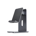 Dark space grey aluminium alloy mobile phone holder with adjustable clamp on a desk edge, holding a large tablet.
