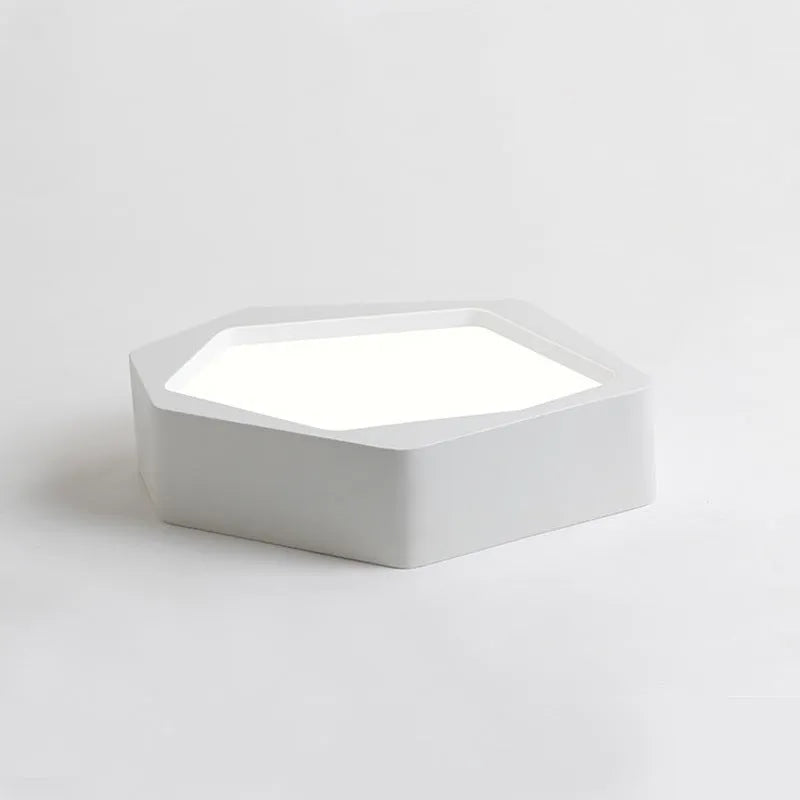 Modern geometric-shaped LED light with black iron frame and remote control on a side table.
