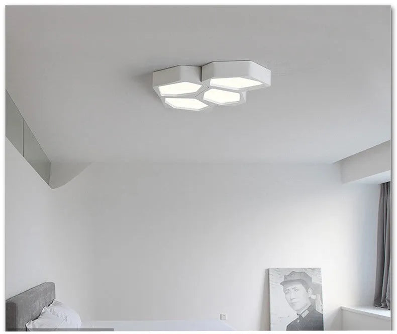 Modern geometric-shaped LED light with black iron frame and remote control on a side table.