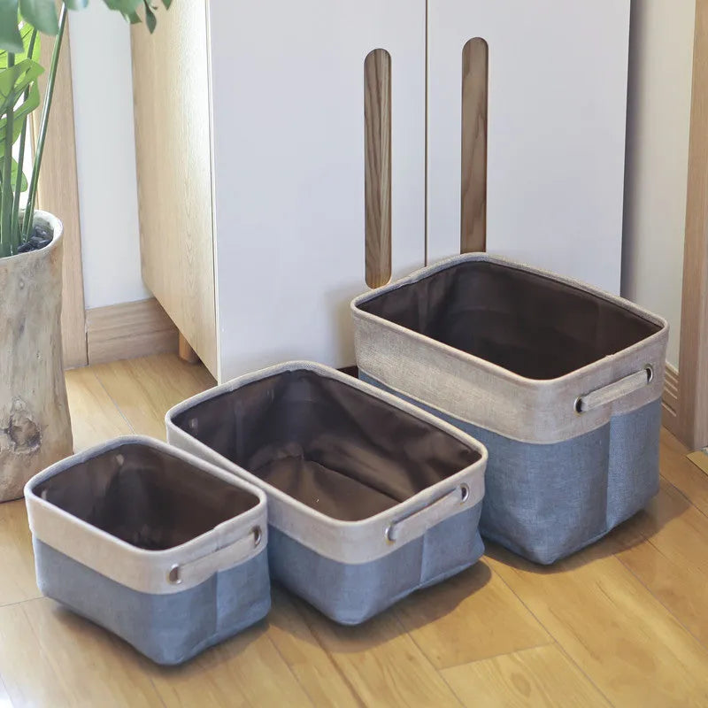 A folded and an unfolded Nordic-style fabric storage box in a neutral colour on a wooden floor.