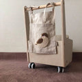 Khaki coloured cotton linen hanging storage bag with one large pocket beside a bed.
