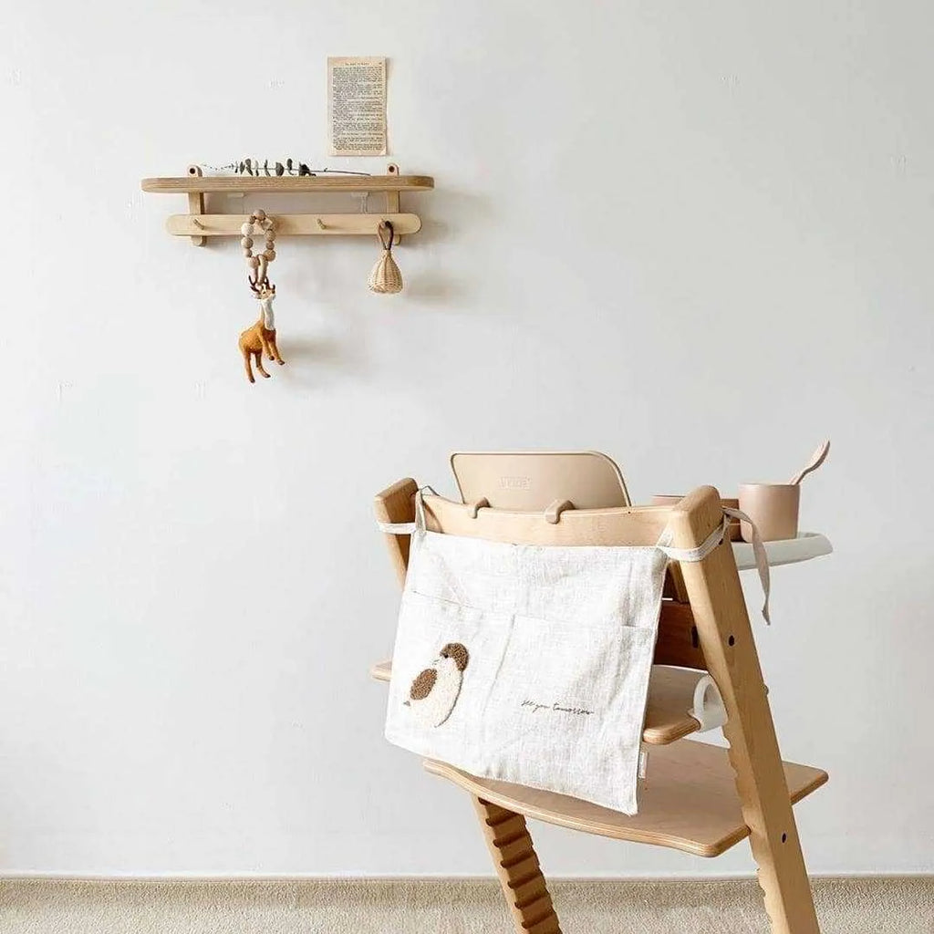 Khaki coloured cotton linen hanging storage bag with one large pocket beside a bed.