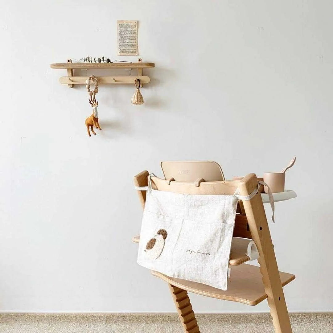 Khaki coloured cotton linen hanging storage bag with one large pocket beside a bed.