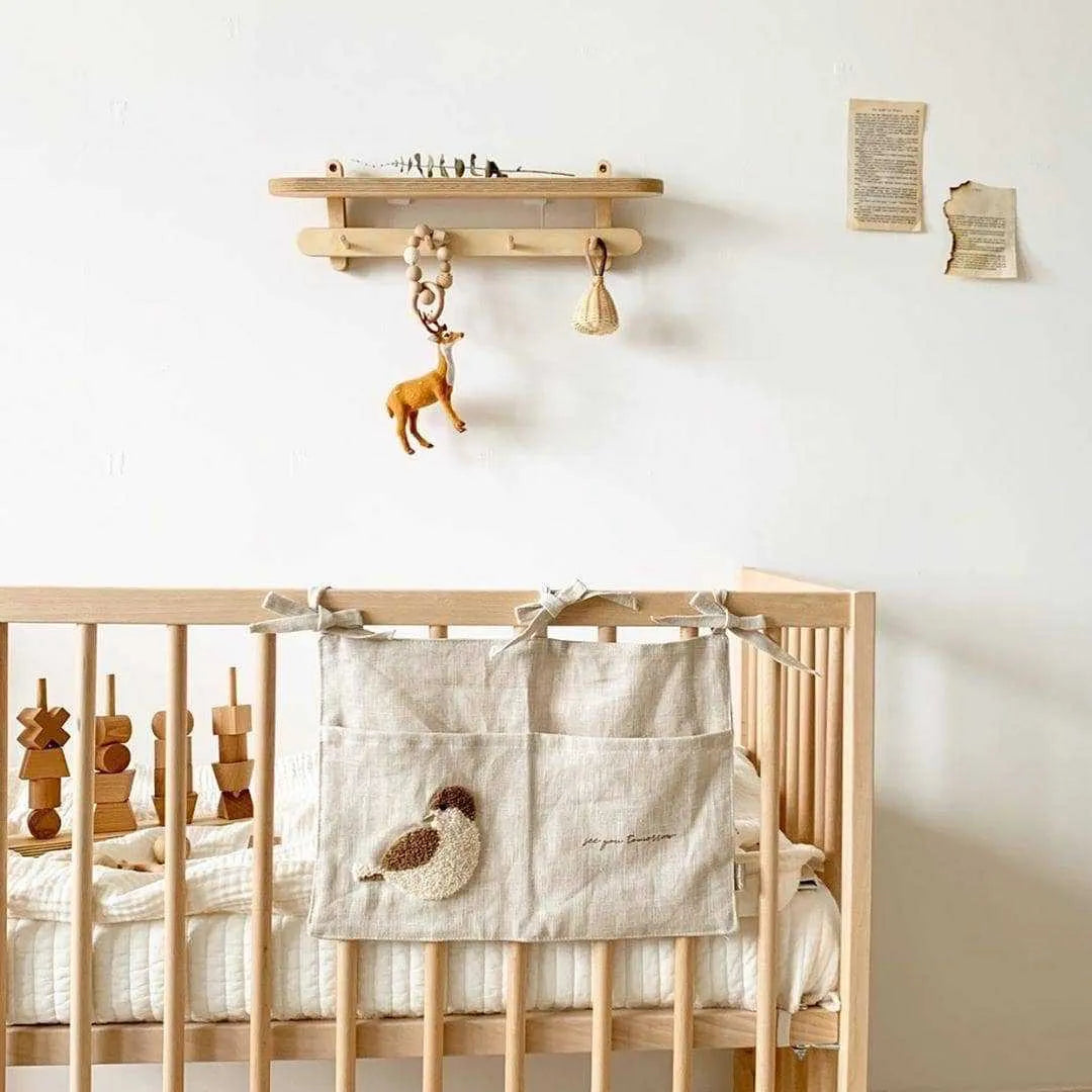 Khaki coloured cotton linen hanging storage bag with one large pocket beside a bed.