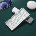 Silver white folding Bluetooth keyboard with stand holding smartphone