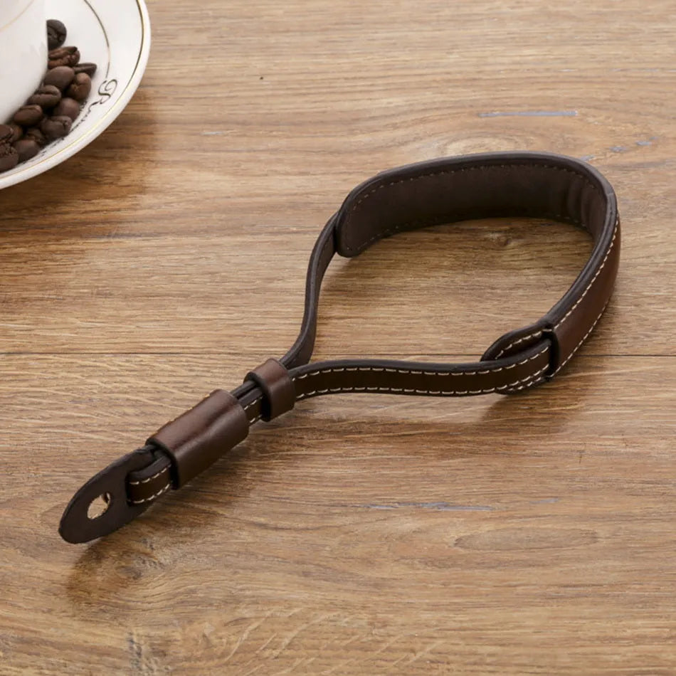 Adjustable black leather camera wrist strap attached to a digital camera body