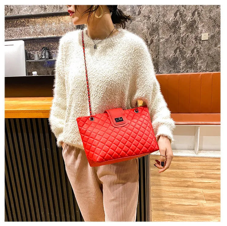 Large women's PU leather tote bag with lock closure and chain shoulder strap in horizontal square shape on white background
