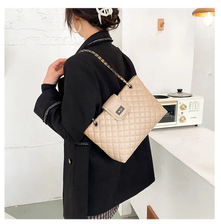 Large women's PU leather tote bag with lock closure and chain shoulder strap in horizontal square shape on white background