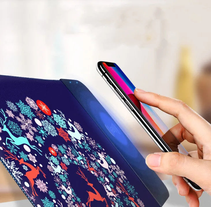 Black cartoon wireless charging mouse pad with glowing RGB lights on a desk.