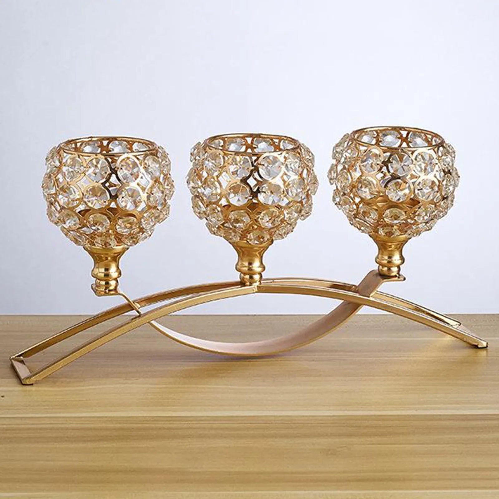 Gold crystal candle holder with geometric wrought iron frame on a table surface
