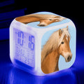 Small square white LED digital alarm clock on a wooden table.