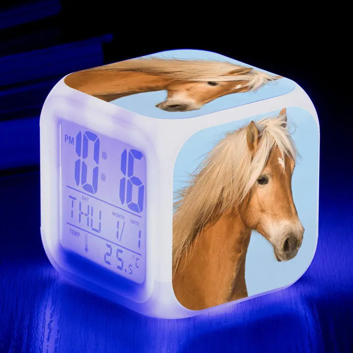 Small square white LED digital alarm clock on a wooden table.