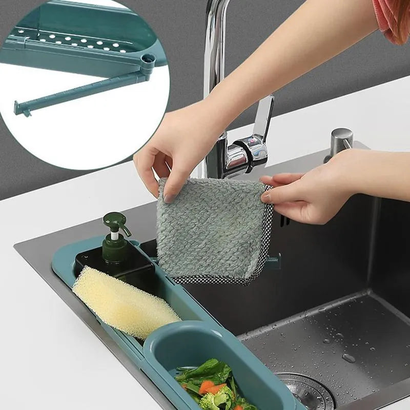 Blue grey telescopic sink rack holding a sponge and soap bar next to a kitchen tap