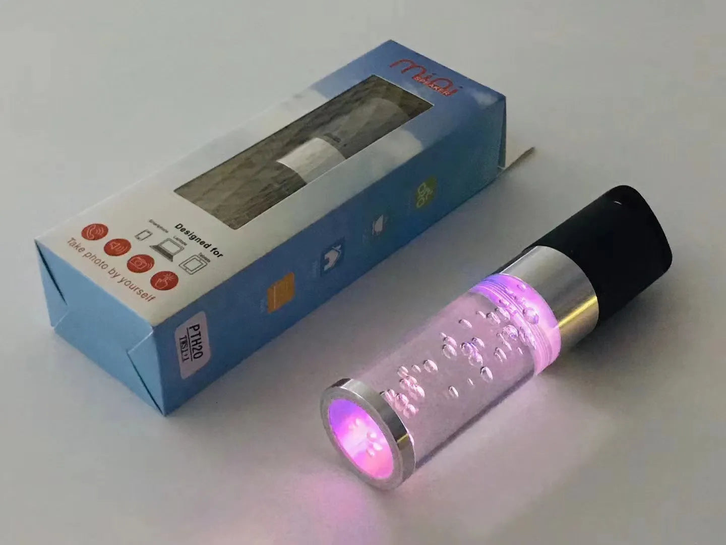 Pink portable Bluetooth speaker with illuminated crystal light panel on front, showing compact size.