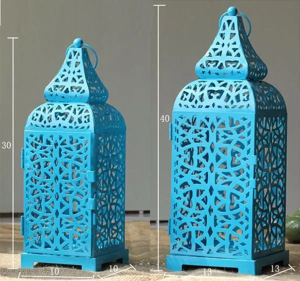A blue hollow iron candelabra with geometric cut-outs in a Moroccan lantern style, holding a candle.