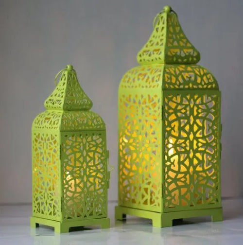 A blue hollow iron candelabra with geometric cut-outs in a Moroccan lantern style, holding a candle.