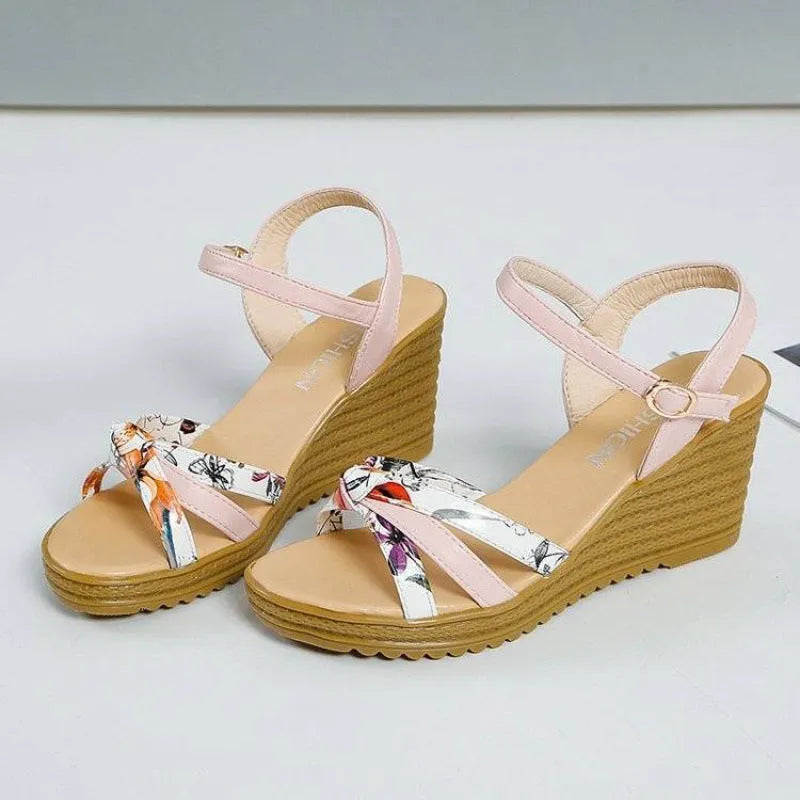 Women's pink wedge heel sandals with a single adjustable buckle strap on a white background.