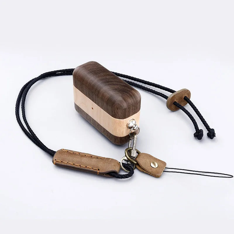 Solid walnut wood protective sleeve for Apple AirPods with attached brown lanyard on a wooden table.