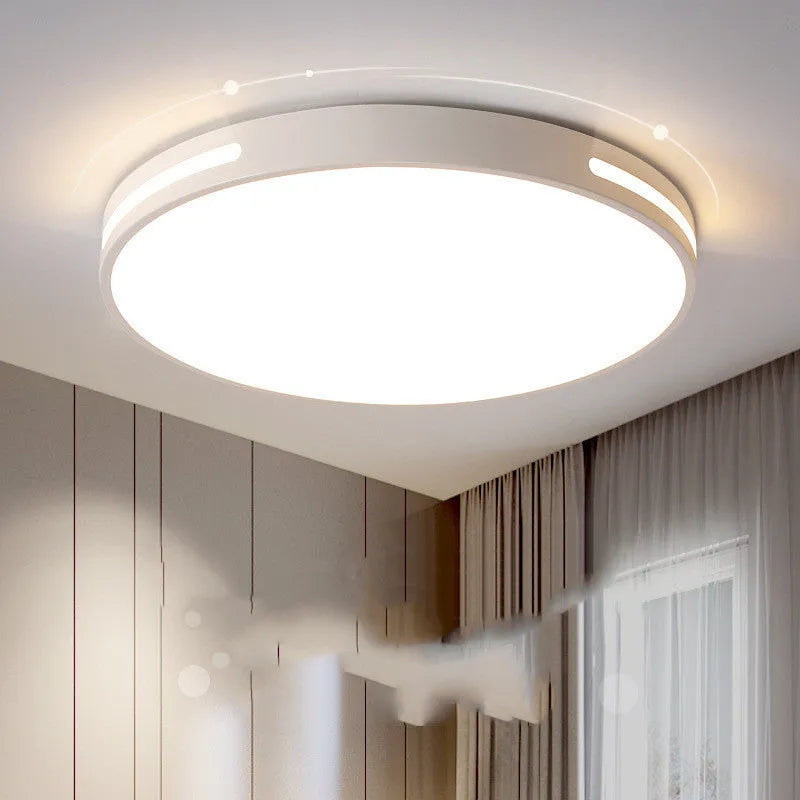 Round modern acrylic ceiling lamp with remote control in white light on a room ceiling.