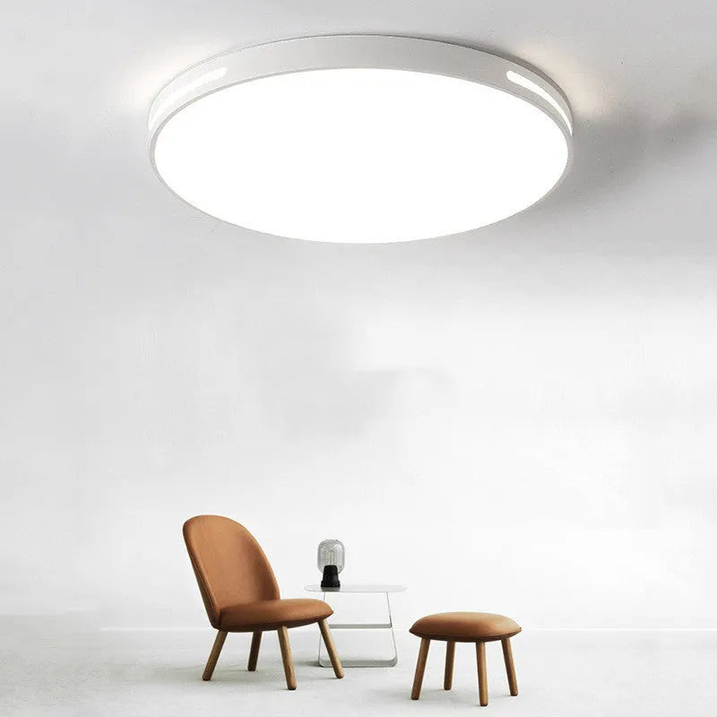 Round modern acrylic ceiling lamp with remote control in white light on a room ceiling.