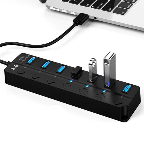 Black 7-port USB 3.0 hub with external power adapter on a desk