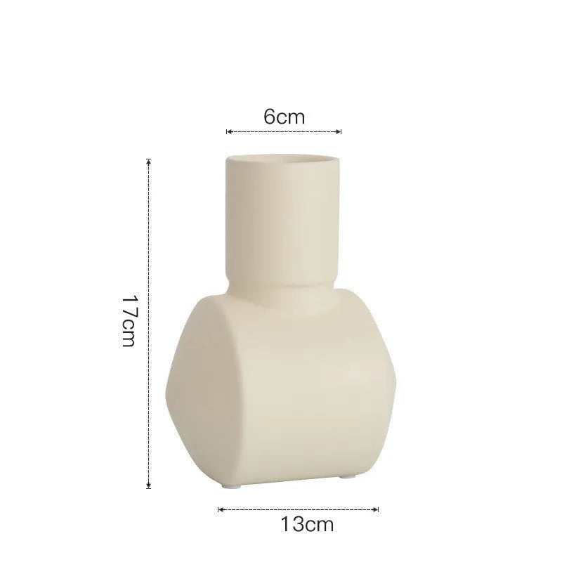Simple hammer-shaped ceramic vase in a Morandi colour glaze on a wooden cabinet.
