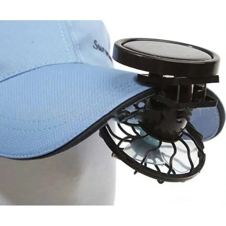 Black portable solar panel fan with a clip, shown outdoors for camping cooling.