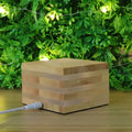 Solid wood square LED night light with warm white light on a wooden bedside table