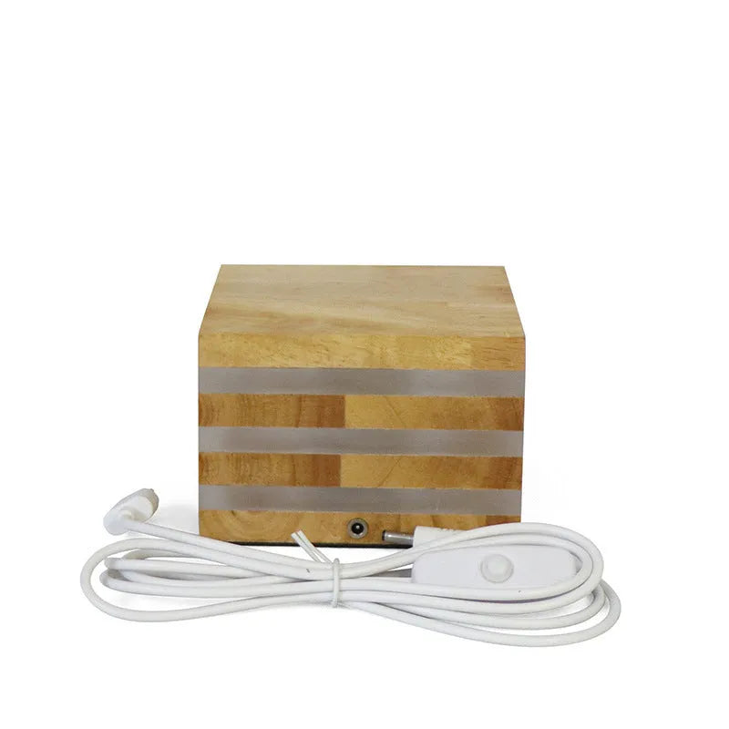 Solid wood square LED night light with warm white light on a wooden bedside table