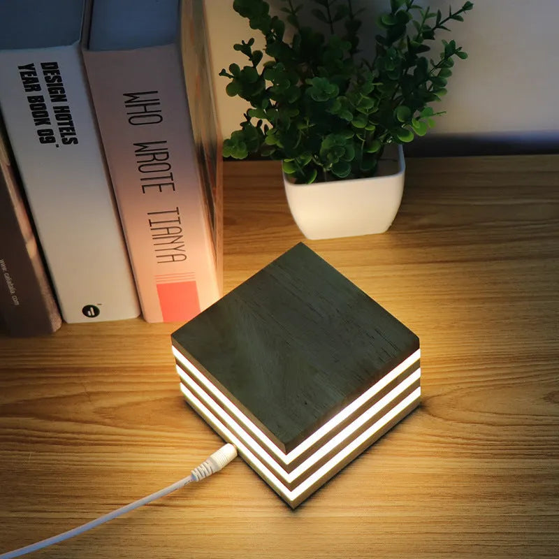 Solid wood square LED night light with warm white light on a wooden bedside table