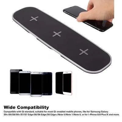 A black universal Qi wireless charging pad on a wooden desk next to a smartphone.